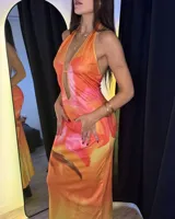 Vestido midi de corte al cuerpo con estampado abstracto en tonos naranja, amarillo y rosa. Tiene escote halter con abertura en el pecho y espalda descubierta.