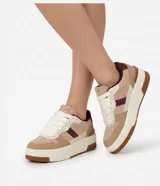Championes de mujer Satinato con diseño de bloques de color en tonos beige, tostado, blanco y detalles en bordó. Cuentan con suela caja alta, cordones gruesos blancos y acabados con textura aterciopelada.