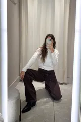 Pantalón de jean corte wide leg color marrón oscuro, con tiro medio y cierre frontal con botón metálico.