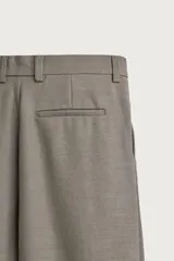 Pantalón relaxed fit de color blanco off-white, confeccionado en tejido con lino. Cuenta con pliegues frontales en la cintura, bolsillos delanteros y cierre frontal con cremallera y botón.