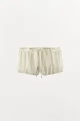 Shorts de tiro bajo con diseño abullonado, confeccionado en tejido ligero con sutiles rayas verticales. Presenta cintura elástica ajustable con cordón y detalle de volantes en la parte superior.