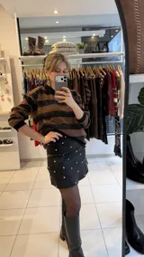 Falda corta de gabardina elastizada color negro, con diseño de tachas metálicas plateadas distribuidas por toda la prenda.