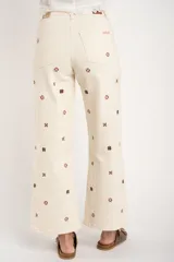 Jean de corte recto y tiro medio, color off-white, con diseño de pequeños bordados en forma de cruz distribuidos por toda la prenda.