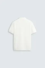 Jersey de punto color verde oliva, de calce relajado (relaxed fit), con cuello solapa y abertura frontal en forma de V. Es de manga corta y presenta acabados en rib en puños y ruedo.