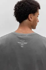 Remera de algodón color marrón con efecto lavado, de corte clásico y cuello redondo. Presenta un pequeño bordado de un pájaro en el pecho.