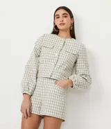 Campera de algodón con estampado cuadrille en tonos verde claro y blanco. Presenta cuello redondo, cierre frontal con botones, mangas largas con puños elásticos y bolsillos frontales tipo parche.