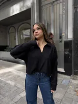 Buzo de punto color negro con cuello polo abierto, mangas largas y diseño holgado de corte corto.