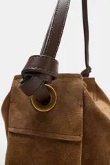 Bolso de mano formato alargado confeccionado en piel, con doble asa, una de mano y otra de hombro, con detalle de nudos y ojales metálicos. Cuenta con cierre mediante solapa y cremallera, y bolsillo interior con cremallera.