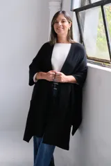 Poncho abierto de tejido de punto color negro, con mangas tres cuartos y bolsillos laterales.