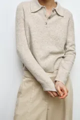 Jersey de lana 100% color beige, con cuello polo, manga larga y botones delanteros.