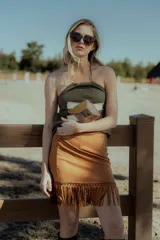 Top strapless negro confeccionado en gamuza con apliques geométricos de cuero en tonos beige y marrón. Presenta flecos en el ruedo.