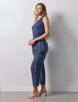 Pantalón de algodón estampado a rayas verticales azules y blancas, marca Erika. Tiene pretina elastizada, bolsillos delanteros, ruedo lateral con tajo y botones decorativos.