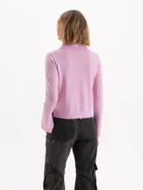 Sweater de punto color rosa, con cuello polo, cierre frontal con botones y mangas largas con puños acampanados.