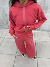 Conjunto deportivo de dos piezas en color rojo, compuesto por un buzo corto con capucha y un pantalón de jogging con cintura elástica.