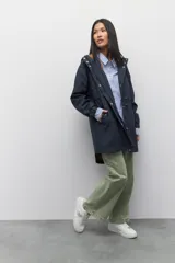 Piloto verde militar de manga larga con capucha y forro de color amarillo. Cuenta con dos bolsillos laterales con solapa, cordones ajustables, elástico en los puños, cierre y botones metálicos.