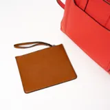 Cartera tipo tote de cuero sintético color rojo con doble asa corta y correa larga desmontable. Tiene un bolsillo externo con cierre y tirador de cuero.