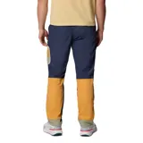 Pantalón cortavientos de corte recto, color azul marino con detalles en naranja y verde oliva. Presenta cintura elástica ajustable, bolsillos laterales y un bolsillo con cremallera en el muslo. Confeccionado con tecnología Omni-Shield que ofrece repelencia al agua y a las manchas.
