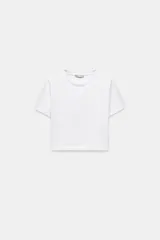 Remera corta de color blanco, corte ajustado, cuello redondo y mangas cortas.