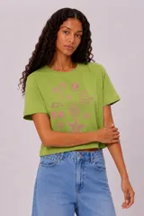 Remera de manga corta y cuello redondo, color verde, con diseño holgado y estampado frontal de temática playera en color rosado.