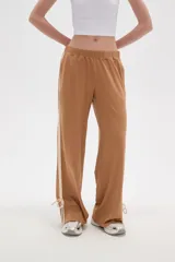 Pantalon deportivo de corte recto y tiro medio, color beige oscuro. Presenta una banda lateral en tono crema y aberturas ajustables con cordones en los tobillos. Cuenta con cintura elástica.