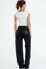 Jean de tiro medio-alto, color negro lavado, de corte recto y holgado. Presenta un gran estampado de estrella en color gris oscuro con brillo en los bolsillos traseros.