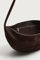 Bolso de hombro con diseño de media luna, confeccionado en piel con acabado de serraje. Cuenta con un asa integrada y cierre principal mediante cremallera.