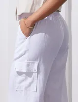 Pantalón de lino color blanco, de corte recto y tiro alto. Presenta bolsillos laterales tipo cargo y pretina elastizada en la parte trasera.