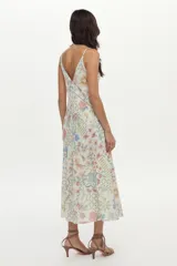 Vestido midi de lino y viscosa color crudo con estampa exclusiva multicolor, escote en V, breteles regulables, bolsillos laterales y detalles de vainillas decorativas.