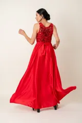 Vestido largo rojo con cuerpo de lentejuelas y falda de satén con caída fluida. Presenta escote redondo, sin mangas y un lazo en la cintura.