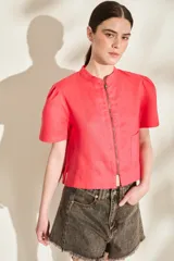 Blusa de lino color amarillo, con cuello mao, cierre frontal con cremallera y mangas cortas abullonadas. Cuenta con un bolsillo aplicado en el frente.