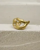 Brazalete abierto de diseño orgánico y voluminoso, con acabado metálico brillante. Su forma irregular y ergonómica permite un ajuste cómodo en la muñeca o antebrazo.