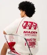 Remera oversized de color blanco marfil con detalles en rojo, cuello redondo, mangas cortas y grandes estampas tipográficas y gráficas en la espalda.