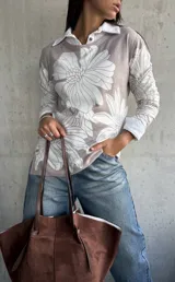 Sweater de punto con diseño floral en tonos beige y blanco, cuello tipo polo y mangas largas.