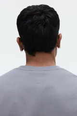 Remera gris de corte relajado, confeccionada en punto liviano con cuello redondo ribeteado, hombros caídos y mangas cortas.