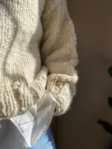 Sweater de lana color crema, tejido a mano con punto grueso.