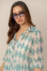 Vestido midi turquesa y blanco con estampado de rombos, cuello camisero, cierre frontal con botones y mangas cortas abullonadas. Cuenta con recortes fruncidos en la falda.
