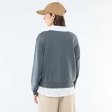 Buzo de cuello redondo color gris oscuro con estampa frontal estilo universitario en color blanco. Presenta un diseño de doble capa con cuello y ruedo de camisa blanca incorporados, mangas largas con puños elásticos y corte holgado.
