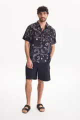 Bermuda cargo negra con cintura elastizada y cordón ajustable, de corte holgado y bolsillos laterales con solapa.