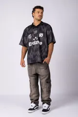 Camiseta de estilo futbolero con cuello polo, manga corta y corte relajado. Presenta un estampado abstracto en tonos grises y negros, con el número 15, el logo de la marca y la palabra Endzone en el frente.