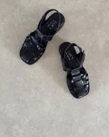 Sandalias tipo guillermina de cuero vacuno color negro, con diseño de tiras entrelazadas, punta cuadrada y tira ajustable en el talón.