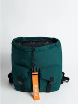 Mochila acolchada de nylon color negro con correas y detalles en rosa pálido. Presenta un cierre principal tipo solapa con hebilla de plástico negra y una cinta colgante con el texto "rusty" en color verde menta.