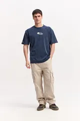 Remera oversize azul marino con efecto lavado, manga corta y cuello redondo. Cuenta con un pequeño estampado gráfico frontal con texto blanco y diseño XL en la espalda.