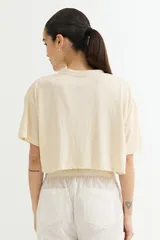 Remera color beige de corte cropped y mangas cortas.