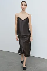 Top de tirantes finos confeccionado en piel 100%, con escote en pico adornado con encaje a contraste y paneles laterales de encaje negro.