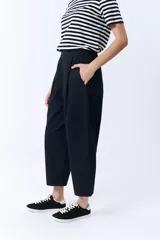 Pantalón negro de corte ancho, con pinzas en la cintura y bolsillos laterales.