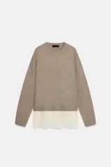 Jersey de punto color beige con cuello redondo y manga larga. Presenta un diseño de bajo combinado con un detalle de encaje en color crema.