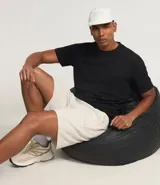 Bermuda deportiva color beige, con cintura elástica ajustable con cordón, bolsillos laterales con cierre y logo estampado en el lateral.