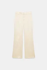 Pantalón de tiro medio de tejido satinado color beige, con bolsillos laterales, pernera recta y detalle de tejido superpuesto en las rodillas. Cierre frontal con cremallera, botón interior y ganchos metálicos ocultos.