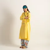 Bata clásica amarilla con textura capitoné y ribete verde en cuello, solapa, puños y cinturón.