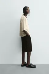 Camiseta de hombre, corte relaxed fit, color beige claro con textura. Presenta cuello redondo amplio y manga corta. Estampado frontal en negro con texto que incluye "Los Angeles".